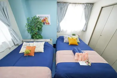 two beds in a room with blue walls at Shamrock Aoto 101 Cozy Tokyo Stay Near Station Airport Disney Access in Tokyo