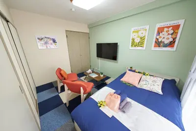 a bedroom with a bed and a chair and a television at Shamrock Aoto 101 Cozy Tokyo Stay Near Station Airport Disney Access in Tokyo