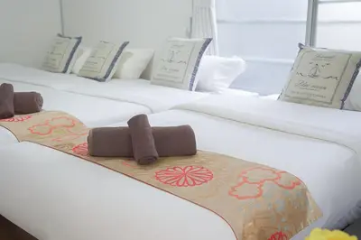 a row of three white beds with towels on them at \u65b0\u5bbf5\u5206\u96a0\u308c\u5bbf in Tokyo