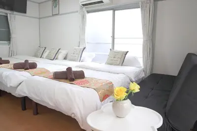 two beds in a room with a table and a couch at \u65b0\u5bbf5\u5206\u96a0\u308c\u5bbf in Tokyo