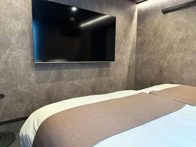 a bedroom with a bed with a tv on the wall at EKVOLI ROPPONGI TOKYO, Private Hotel in Tokyo
