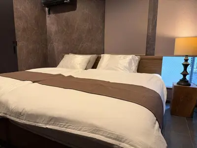 a large bed with white sheets and pillows in a bedroom at EKVOLI ROPPONGI TOKYO, Private Hotel in Tokyo