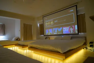 a bedroom with two beds and a large screen at SIC Hotel Shinjuku - Shin Nakano in Tokyo