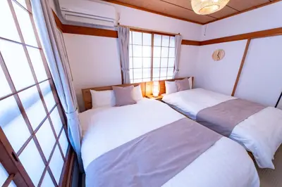 two beds in a small room with windows at Haleluana SHIBAMATA in Tokyo