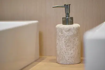 a white soap dispenser sitting next to a bath tub at Tsubomi Shibuya in Tokyo