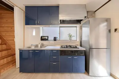 a kitchen with blue cabinets and a stainless steel refrigerator at Kasai Cozy House in Tokyo