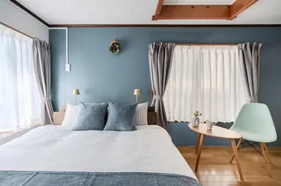 a bedroom with blue walls and a bed and a table at Kasai Cozy House in Tokyo