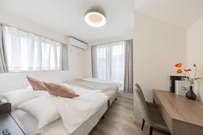 a white bedroom with a bed and a desk at Akari HOTEL in Tokyo