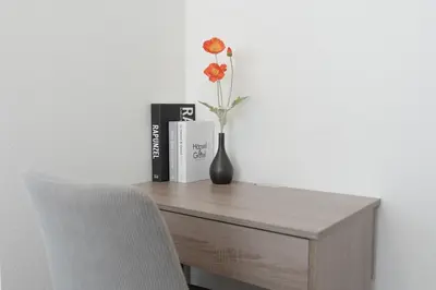 a vase with a flower on a desk with a book at Akari HOTEL in Tokyo
