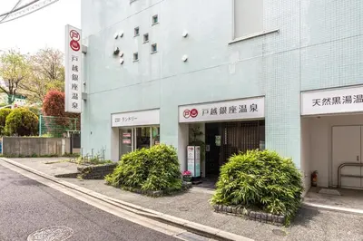 a blue building with bushes in front of a street at Akari HOTEL in Tokyo