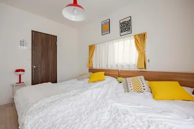 a bedroom with a large white bed with yellow pillows at sMS\u8db3\u7acb2\u4e01\u76ee in Tokyo