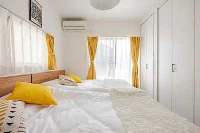 a bedroom with a large white bed with yellow pillows at sMS\u8db3\u7acb2\u4e01\u76ee in Tokyo