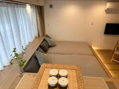 a living room with two beds and a table at Akatsuki Ueno Park \u4e0a\u91ce\u52d5\u7269\u5712 \u4e0a\u91ce\u516c\u5712\u5f92\u6b69 4\u5206 in Tokyo