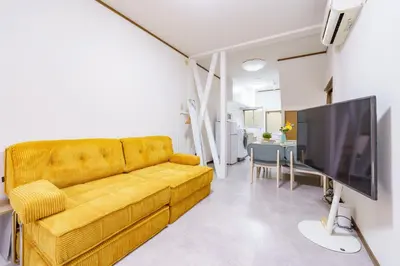 a living room with a yellow couch and a flat screen tv at Konoha Sangenjaya DZ4 in Tokyo