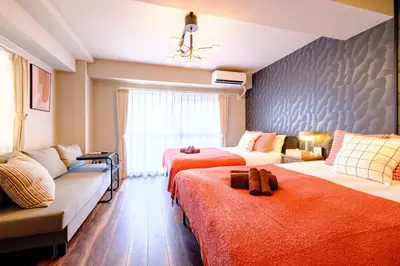 a bedroom with two beds and a couch at Living Stay Plum Residence - Authentic Tokyo Stay - Direct to HND 20m & Shinagawa in Tokyo