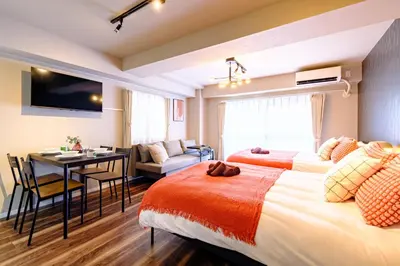 a hotel room with two beds and a dining room at Living Stay Plum Residence - Authentic Tokyo Stay - Direct to HND 20m & Shinagawa in Tokyo
