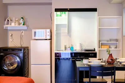a kitchen with a refrigerator and a table with a microwave at Living Stay Plum Residence - Authentic Tokyo Stay - Direct to HND 20m & Shinagawa in Tokyo
