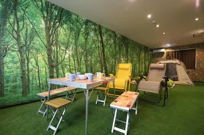a room with a table and chairs and a wall of trees at \u30e9\u30dd\u30fc\u30eb\u6771\u5411\u5cf6 in Tokyo