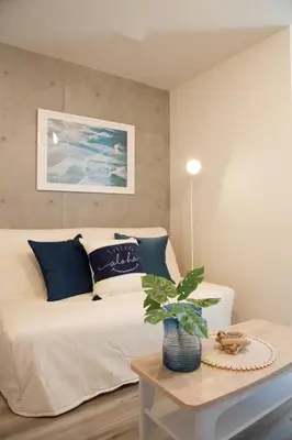 a bedroom with a white bed with blue pillows and a table at TOMALCO INN NAKANO 2 3F Flat 2 Bath 13 min to Shinjuku from Honancho in Tokyo