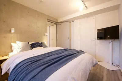 a bedroom with a bed and a tv on a wall at TOMALCO INN NAKANO 2 3F Flat 2 Bath 13 min to Shinjuku from Honancho in Tokyo