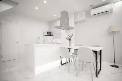 a white kitchen with a table and white chairs at Brand New Luxury Suite 7 min to Omotesando 2 min to Shibuya in Tokyo