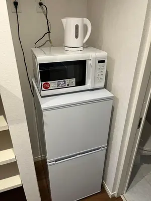 a microwave sitting on top of a refrigerator at \u30af\u30ea\u30aa-\u30e9\u30e2\u30fc\u30c9\u5927\u68ee in Tokyo