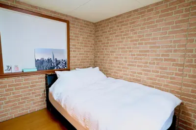 a bedroom with a brick wall and a white bed at Shinjuku Y HOTEL II 1 minute to 7-Eleven 6DK 2 bathrooms in Tokyo