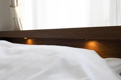 a white bed with a wooden headboard and a window at \u7acb\u5730\u6700\u9ad8 \u65b0\u5bbf\u6b4c\u821e\u4f0e\u753a \u65b0\u5bbf\u99c5\u5f92\u6b69\u570f\u5185 \u6700\u59273\u540d\u69d8\u307e\u3067\u5bbf\u6cca\u53ef\u80fd 6\u8def\u7dda\u5229\u7528\u53ef\u80fd 6\u6b73\u4ee5\u4e0b\u306f\u7121\u6599\u3067\u3059 in Tokyo