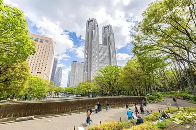 a group of people walking in a park with tall buildings at \u65b0\u5bbfClassy House in Tokyo