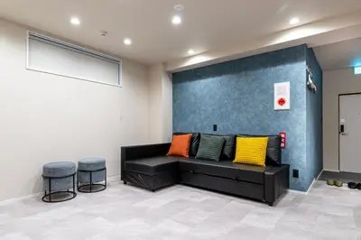 a living room with a black couch and two stools at Sharil Shiina-machi in Tokyo