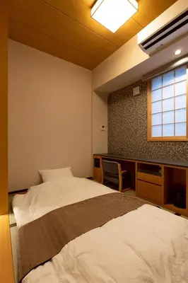 a room with two beds and a desk and a window at Hotel Matsunoi Shurin in Tokyo