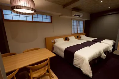 a bedroom with two beds and a table and chairs at Hotel Matsunoi Shurin in Tokyo