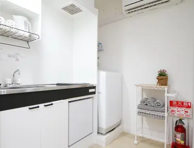 a white kitchen with a sink and a refrigerator at Tokyo Ueno Mia Hotel in Tokyo