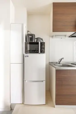 a kitchen with a microwave on top of a refrigerator at \u677f\u6a4b\u533a yuga house\u99c5\u8fd1102 in Tokyo