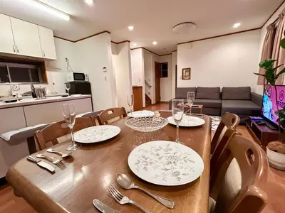 a dining room table with plates and wine glasses on it at AiES\u65b0\u5c0f\u5ca9 \u65b0\u5c0f\u5ca9\u7ad9\u8d708\u5206 \u7e41\u534e\u5546\u5e97\u8857\u65c1 \u6700\u592712\u4eba \u76f4\u8fbe\u673a\u573a\u79cb\u53f6\u539f\u65b0\u5bbf \u65c5\u9986\u5185\u5e26\u514d\u8d39\u505c\u8f66\u573a\u5ead\u9662\u9732\u53f0 \u90bb\u516c\u56ed in Tokyo