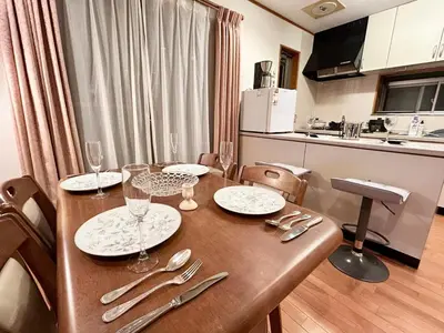 a table with plates and silverware on it in a kitchen at AiES\u65b0\u5c0f\u5ca9 \u65b0\u5c0f\u5ca9\u7ad9\u8d708\u5206 \u7e41\u534e\u5546\u5e97\u8857\u65c1 \u6700\u592712\u4eba \u76f4\u8fbe\u673a\u573a\u79cb\u53f6\u539f\u65b0\u5bbf \u65c5\u9986\u5185\u5e26\u514d\u8d39\u505c\u8f66\u573a\u5ead\u9662\u9732\u53f0 \u90bb\u516c\u56ed in Tokyo