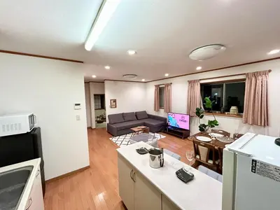 a living room with a couch and a table at AiES\u65b0\u5c0f\u5ca9 \u65b0\u5c0f\u5ca9\u7ad9\u8d708\u5206 \u7e41\u534e\u5546\u5e97\u8857\u65c1 \u6700\u592712\u4eba \u76f4\u8fbe\u673a\u573a\u79cb\u53f6\u539f\u65b0\u5bbf \u65c5\u9986\u5185\u5e26\u514d\u8d39\u505c\u8f66\u573a\u5ead\u9662\u9732\u53f0 \u90bb\u516c\u56ed in Tokyo