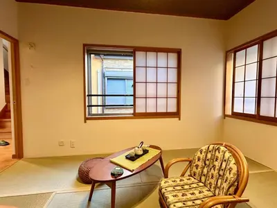 a room with a table and a chair and windows at AiES\u65b0\u5c0f\u5ca9 \u65b0\u5c0f\u5ca9\u7ad9\u8d708\u5206 \u7e41\u534e\u5546\u5e97\u8857\u65c1 \u6700\u592712\u4eba \u76f4\u8fbe\u673a\u573a\u79cb\u53f6\u539f\u65b0\u5bbf \u65c5\u9986\u5185\u5e26\u514d\u8d39\u505c\u8f66\u573a\u5ead\u9662\u9732\u53f0 \u90bb\u516c\u56ed in Tokyo
