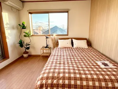 a bedroom with a bed with a plaid blanket and a window at AiES\u65b0\u5c0f\u5ca9 \u65b0\u5c0f\u5ca9\u7ad9\u8d708\u5206 \u7e41\u534e\u5546\u5e97\u8857\u65c1 \u6700\u592712\u4eba \u76f4\u8fbe\u673a\u573a\u79cb\u53f6\u539f\u65b0\u5bbf \u65c5\u9986\u5185\u5e26\u514d\u8d39\u505c\u8f66\u573a\u5ead\u9662\u9732\u53f0 \u90bb\u516c\u56ed in Tokyo