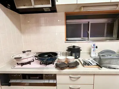 a kitchen with a stove with two pots and pans at AiES\u65b0\u5c0f\u5ca9 \u65b0\u5c0f\u5ca9\u7ad9\u8d708\u5206 \u7e41\u534e\u5546\u5e97\u8857\u65c1 \u6700\u592712\u4eba \u76f4\u8fbe\u673a\u573a\u79cb\u53f6\u539f\u65b0\u5bbf \u65c5\u9986\u5185\u5e26\u514d\u8d39\u505c\u8f66\u573a\u5ead\u9662\u9732\u53f0 \u90bb\u516c\u56ed in Tokyo