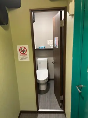 a bathroom with a toilet with a sign on the door at Meguro Midori Hotel in Tokyo