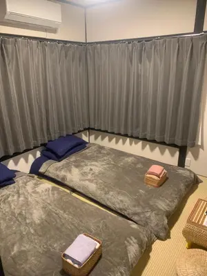 two beds in a room with grey curtains at \u4ec1\u4fe1\u5c0f\u5c4b in Tokyo