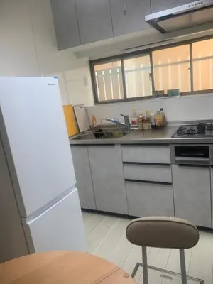 a kitchen with a refrigerator and a table and a chair at \u4ec1\u4fe1\u5c0f\u5c4b in Tokyo