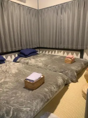 two beds in a room with gray sheets and towels at \u4ec1\u4fe1\u5c0f\u5c4b in Tokyo