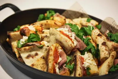 a black pan filled with a pizza with greens at Premium hotel MONday MAIHAMA View 1 in Tokyo