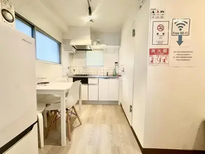 a small kitchen with a white table and a table and chairs at \u6c5f\u5143\u6d45\u8349\u6c11\u6cca in Tokyo