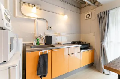 a kitchen with orange cabinets and a sink at Private Apartment HOTEL Ceres Kamiikebukuro 301 in Tokyo
