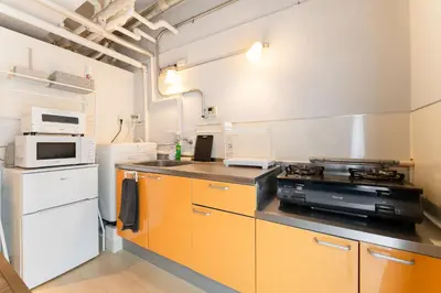 a kitchen with orange cabinets and a stove top oven at Private Apartment HOTEL Ceres Kamiikebukuro 301 in Tokyo