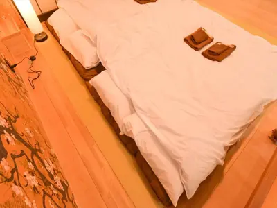a bed with white sheets and a suitcase on it at Sumida Tatekawa House in Tokyo