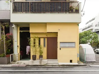 a yellow house with a balcony on top of it at Sumida Tatekawa House in Tokyo